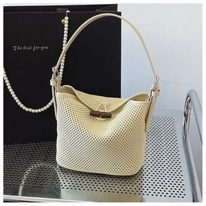 Macro detail of hand-woven beige raffia bucket bag with a classic wooden toggle clasp