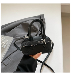 Close-up of black litchi grain leather mini bag with silver buckle and hand for scale