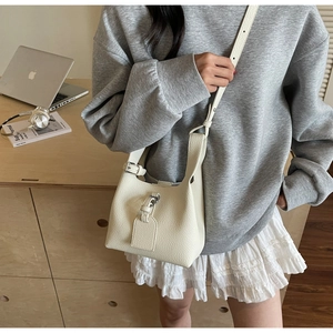 Gros plan du sac seau en cuir grainé blanc crème avec bandoulière ajustable