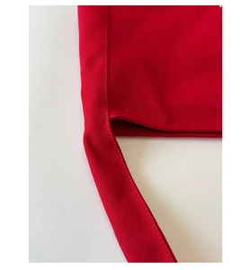 Detailed close-up of reinforced stitching on red heavy canvas tote bag shoulder strap