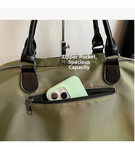 Detail view of military green canvas travel bag showing a front zipper pocket for phone storage