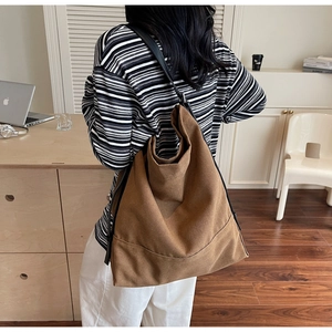 Detail of a large brown canvas bucket bag showing the soft texture and black shoulder strap