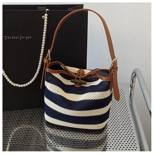 Detail of blue and white striped straw bucket bag with leather strap and wooden button