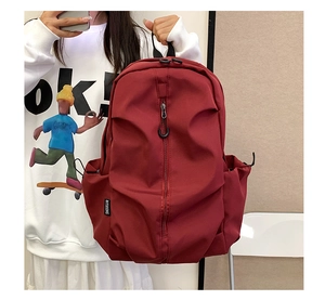 Detail of burgundy waterproof backpack with vertical zipper and side drawstring pocket