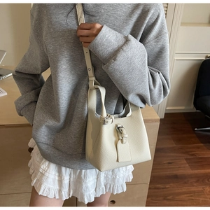 Gros plan détaillé d'un sac seau blanc en cuir grainé avec boucle décorative élégante