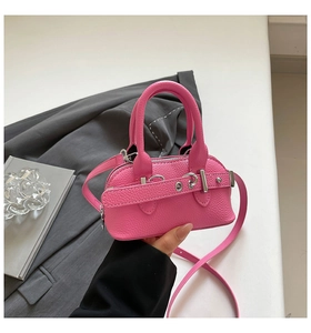 Rose pink mini shell bag with lychee texture held against a grey blazer suit
