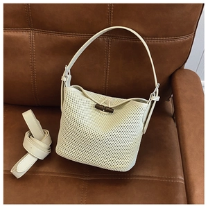 Detail of cream white woven bucket bag with leather trim and vintage wooden toggle closure