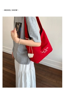 Detail of red canvas tote bag featuring white side drawstring and mini hanging pouch
