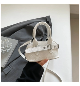 Detail of white lychee leather mini shell bag with silver buckle on grey suit background