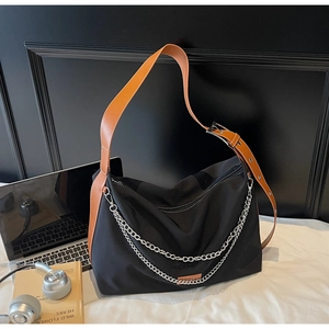 Détail du sac fourre-tout en nylon avec chaînes argentées et étiquette orange décorative