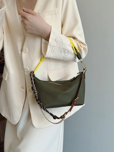 Olive green hobo shoulder bag featuring unique multi-material straps on white blazer
