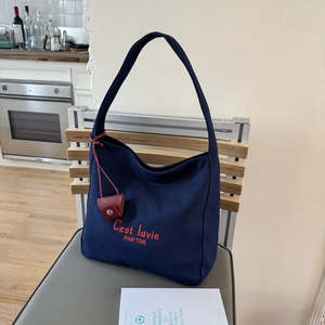 Detail of navy canvas tote bag with red embroidery and matching leather accessory pouch