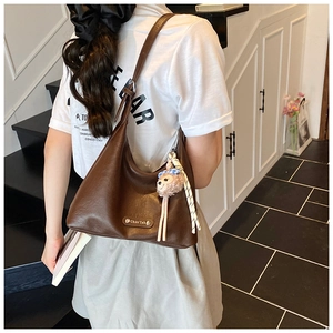 Detail of a deep brown hobo bag with adjustable strap and a cute sheep plush charm
