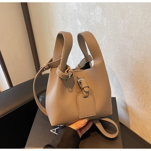 Détail du sac seau en cuir grainé taupe avec fermeture à lanière et boucle métallique