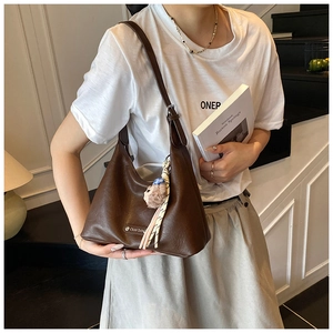 Detail of dark brown leather hobo bag with teddy charm and metallic logo on the front