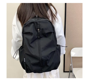 Detail of minimalist black backpack featuring hidden zipper and drawstring side pockets