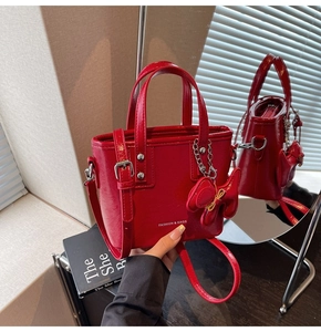 Détail du sac cabas en cuir verni rouge avec boucle argentée et breloque noeud