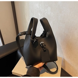 Gros plan d'un sac seau en cuir grainé noir avec boucle métallique et détails de sangle