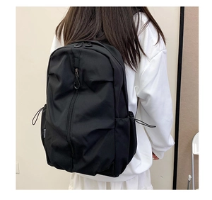 Detail view of black waterproof nylon backpack with drawstring side pockets and sleek design