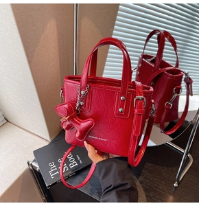Détail d'un petit sac à main rouge en cuir froissé avec bandoulière et bijou