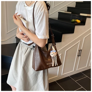 Close-up of vintage brown PU leather shoulder bag with silver buckle and plush pendant