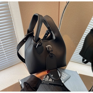 Gros plan d'un sac seau en cuir grainé noir avec détails argentés et texture de qualité