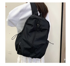Macro detail of black backpack showing side drawstring pocket and durable nylon texture