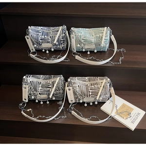 Detail of four colorful striped crossbody bags with pearl chains on wooden steps