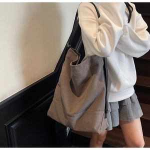 Detail view of large canvas tote bag in taupe with black straps shown on a model