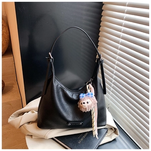 Detail of black pebble grain hobo bag with silver logo plate and plush bear charm