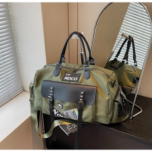 Detailed macro view of olive green travel bag showing rivet flap pocket and 1983 reflective patch