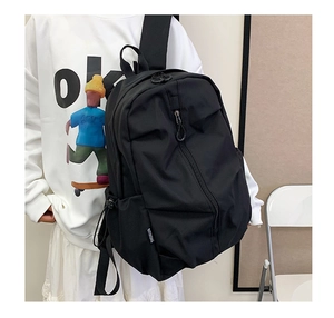 Detail of black nylon backpack featuring a diagonal zipper pocket and adjustable drawstring
