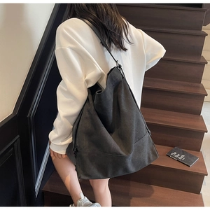 Detail of high-capacity black canvas tote bag with leather strap on wooden stairs