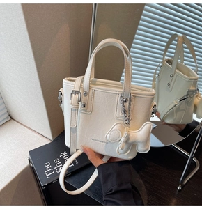 Détail du sac à main blanc en cuir grainé avec finitions argentées et breloque chien