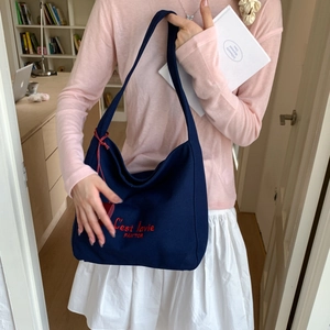 Close-up of navy canvas tote bag with red C'est la vie embroidery and charm detail