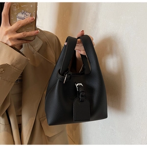 Détail d'un sac seau noir en cuir texturé avec boucle argentée lors d'un selfie miroir