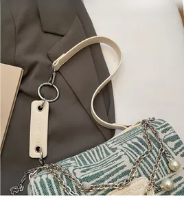 Detailed shot of a woven shoulder bag with silver chains and large pearl charms