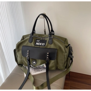 Detail of army green travel bag with vintage patches and black pocket rivets