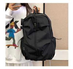 Detail of black nylon backpack featuring side pockets with elastic cords and side label