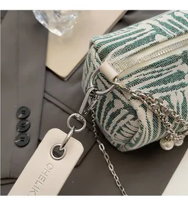 Detail view of green striped jacquard tote with silver chain and pearl pendant