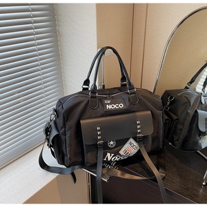 Detail of black sports duffel bag showing NOCO brand patches and metal rivet accents