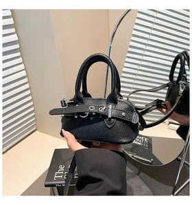Close-up of black lychee grain leather mini shell bag with buckle strap detail