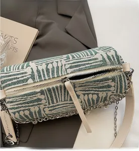 Detail of green and white woven cylinder bag featuring metal chain and pearl shoulder strap
