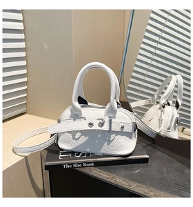 Close-up of white pebble leather texture and metallic buckle on a mini shell bag