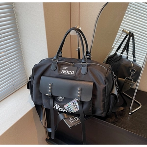 Detail of black nylon travel bag featuring rivet flap pocket and iridescent 1983 tag