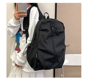 Detail of black casual backpack featuring side drawstring pocket and padded shoulder strap
