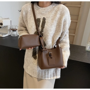 Ensemble sac seau et pochette en cuir marron à motif litchi dans un décor de café