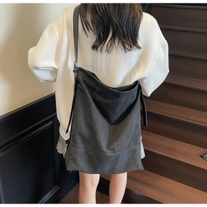 Minimalist black large canvas bucket bag with leather strap worn by a model in interior