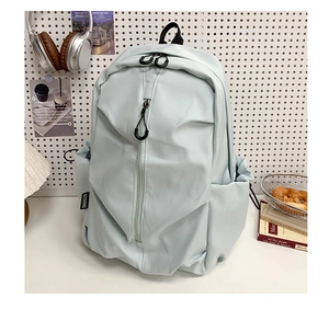 Detailed view of light blue nylon backpack with side pockets on a desk setup