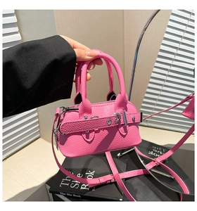 Detail of fuchsia lychee leather mini shell bag with silver studs and top handles